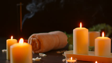 Still-Life-Of-Lit-Candles-With-Green-Plant-Incense-Stick-And-Soft-Towels-Against-Dark-Background-As-Part-Of-Relaxing-Spa-Day-Decor-2